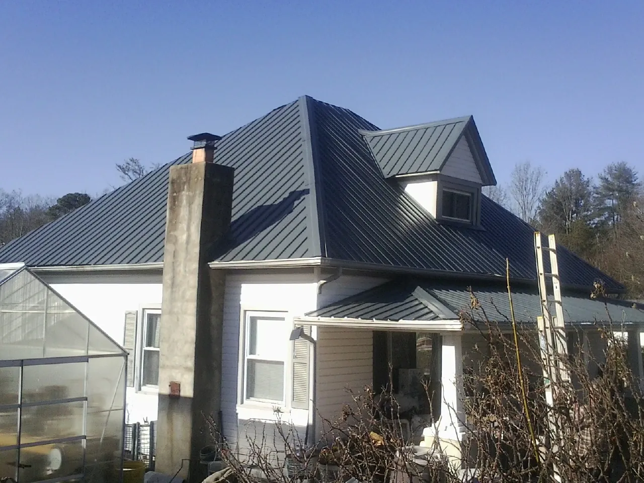 Dark blue standing seam metal roof on a white farmhouse with dormer — Slate & Tile Roof Repair by Roofing Brothers in Red Bank