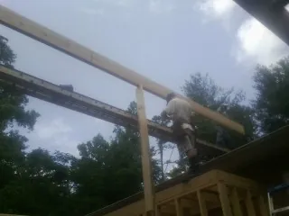 Carpenter setting a ridge beam over a new addition frame — Ice Dam Removal by Roofing Brothers in Red Bank