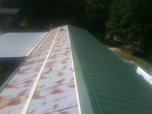 Old rusted panels beside newly installed green metal roofing — Wind Damage Roof Repair by Roofing Brothers in Red Bank