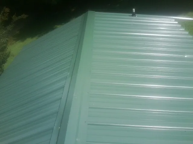 New green metal panels meeting at the ridge of a roof — Flat Roof Repair work by our crew in Red Bank