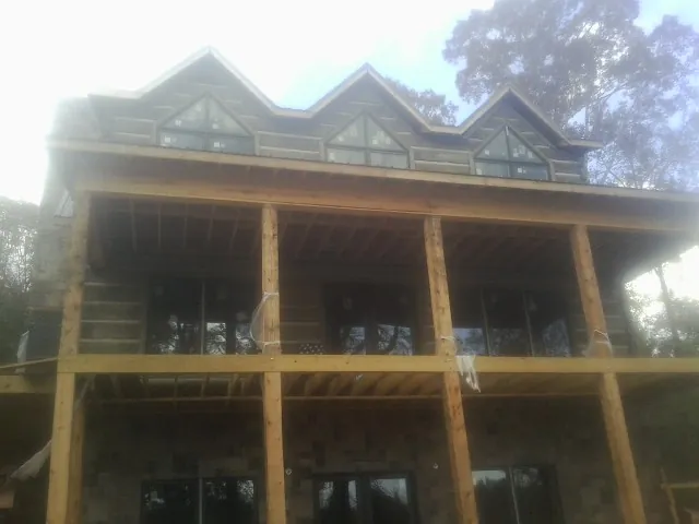 Dormers and porch framing on a large log home under construction — Roof Coating work by our crew in Red Bank