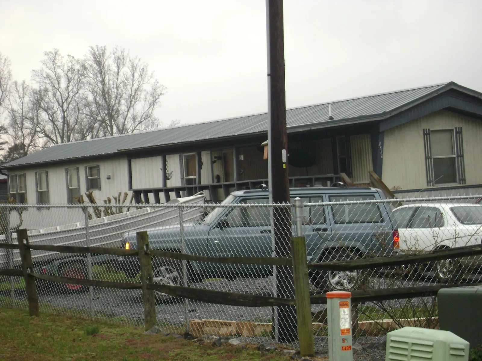 Dark metal roof on a long single story building behind a chain link fence in Red Bank