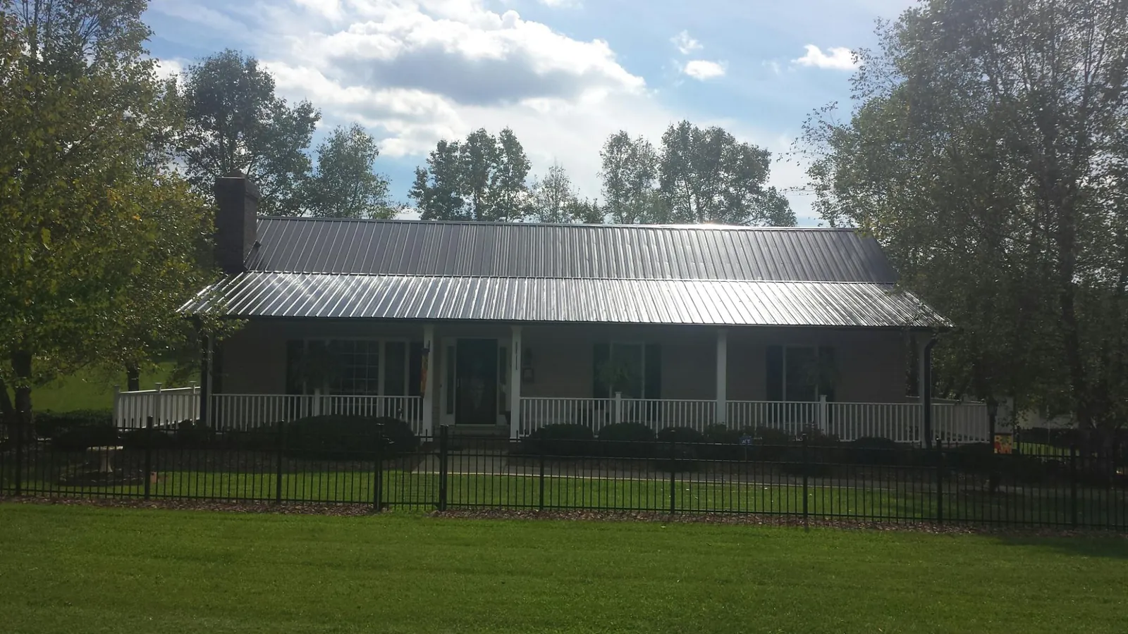 Gray metal roof on a brick ranch with a full width front porch — Gutter Guard Installation work by our crew in Red Bank