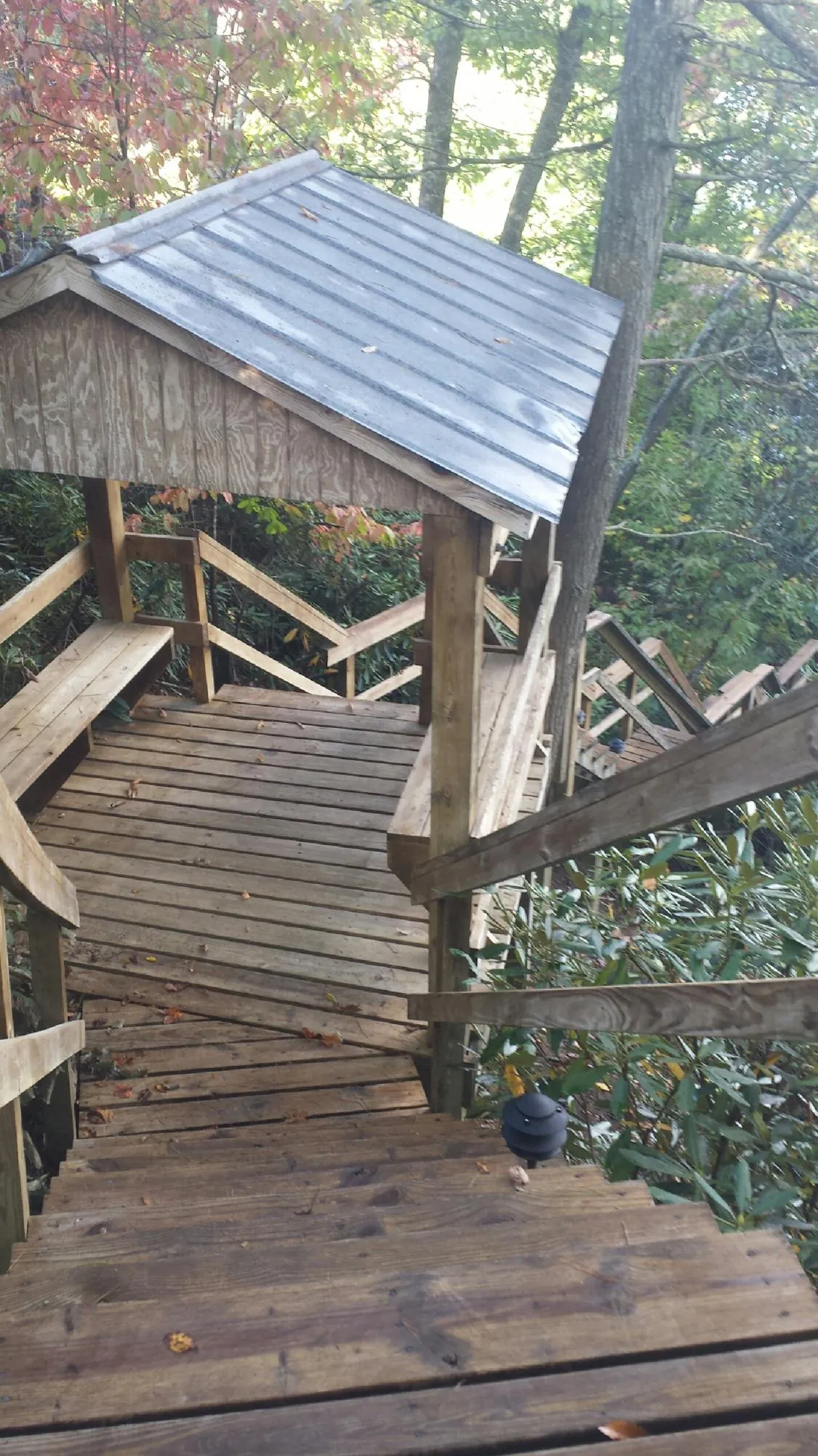 Metal roofed shelter over wooden steps on a wooded walkway — Skylight Repair & Installation work by our crew in Red Bank