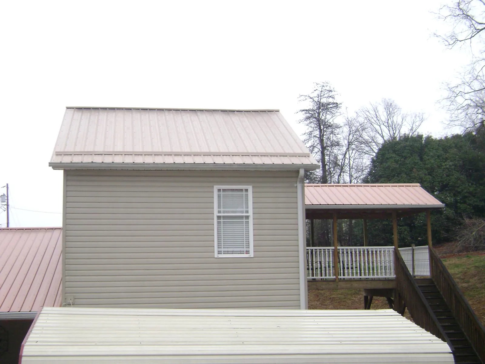 Tan metal roofs on a two story addition and attached porch, from a Roof Replacement job in Red Bank
