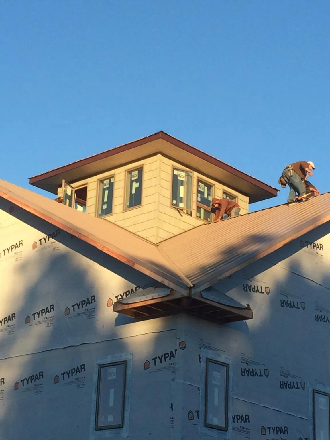 Roofers working around a rooftop cupola on a new metal roof at sunset — Roof Waterproofing in Red Bank by Roofing Brothers